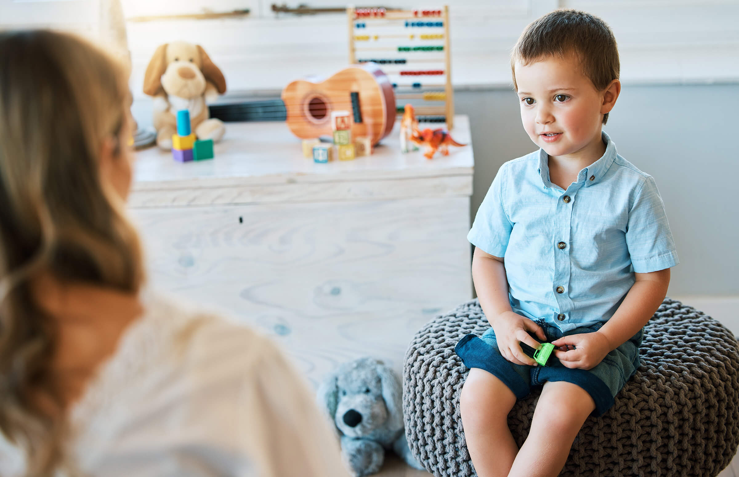 Student sitting on poof chair while teacher talks to them
