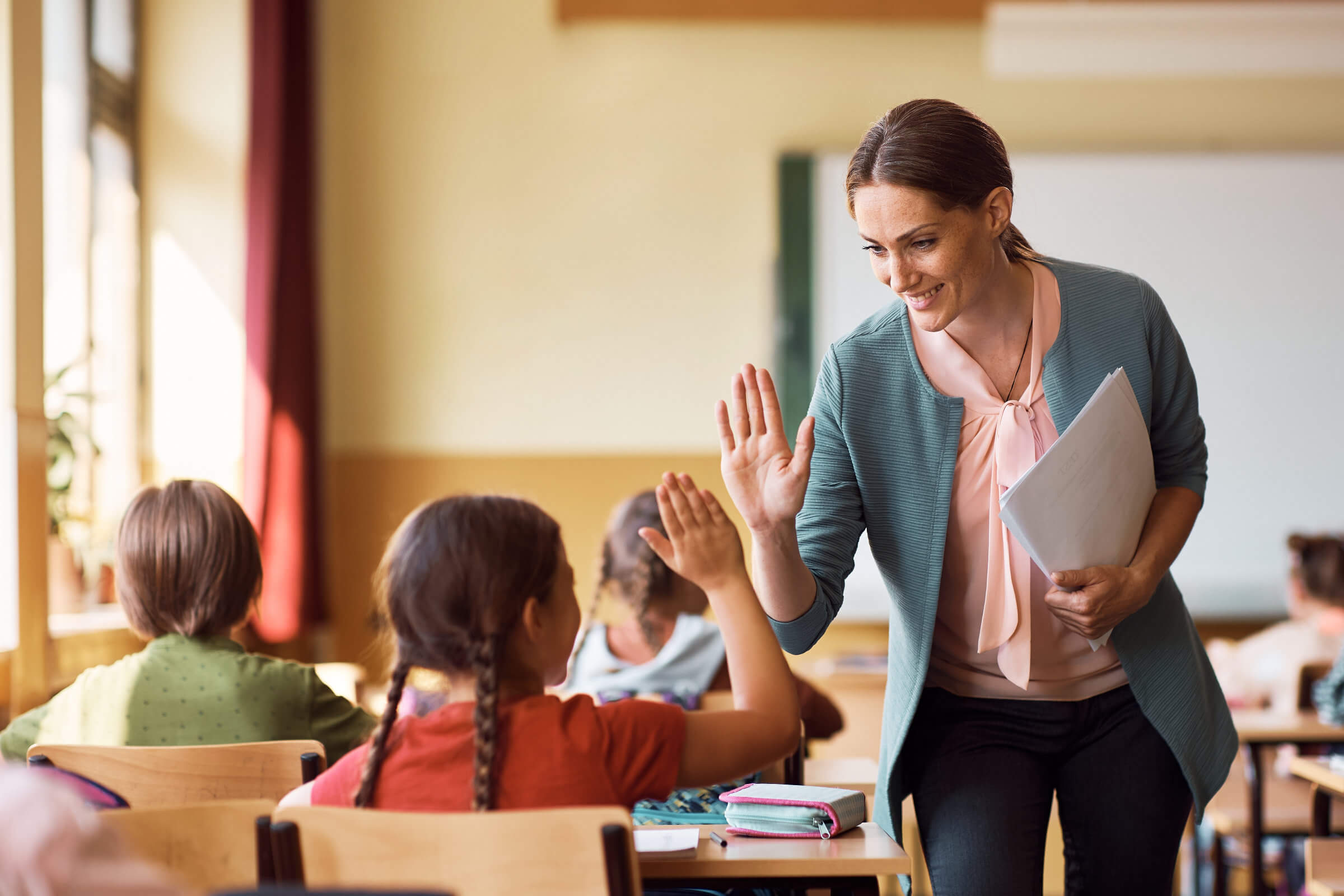 Teacher high-fiving student in classroom