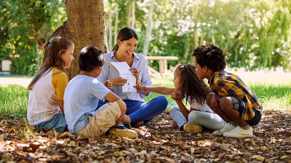 Students and teacher sitting outside under tree